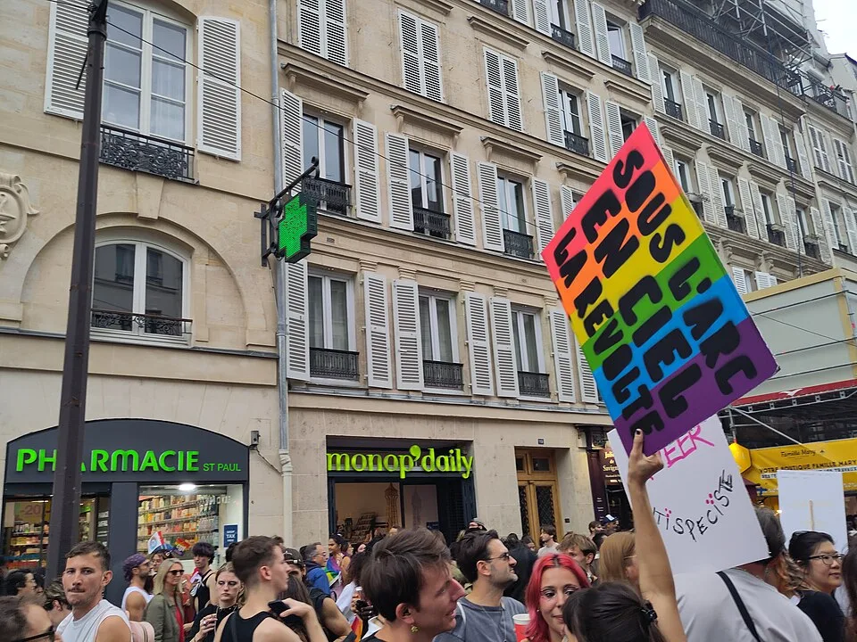 Protest sign reading “Sous l’arc-en-ciel, la révolte” at “Paris Pride — 3 October 2026” in Paris, France.