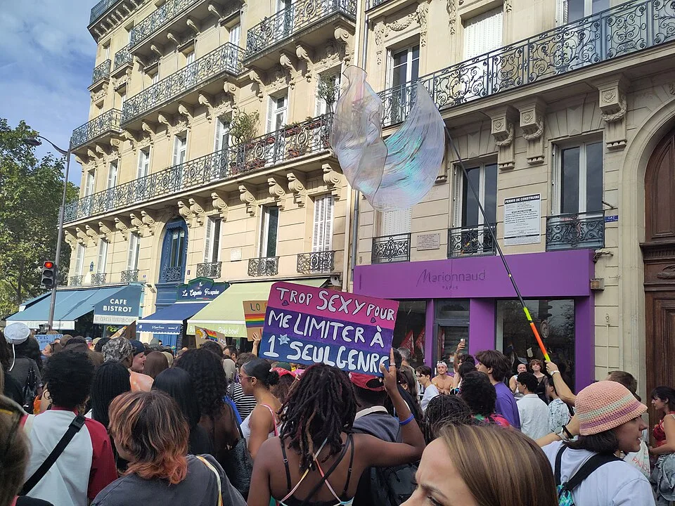 Protest sign reading “Trop sexy pour me limiter à 1 seul genre” at “Paris Pride — 3 October 2026” in Paris, France.
