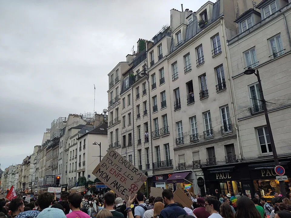 Protest sign reading “On brûlera toutes les deux en enfer, mon ange” at “Paris Pride — 3 October 2026” in Paris, France.