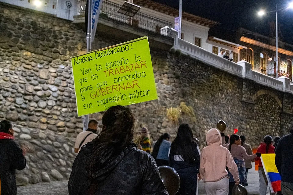 لافتة مظاهرة كُتب عليها «Noboa Desubicado: Ven te enseño lo que es TRABAJAR para que aprendas a GOBERNAR sin represión militar»، صُوّرت في Cuenca, الإكوادور.