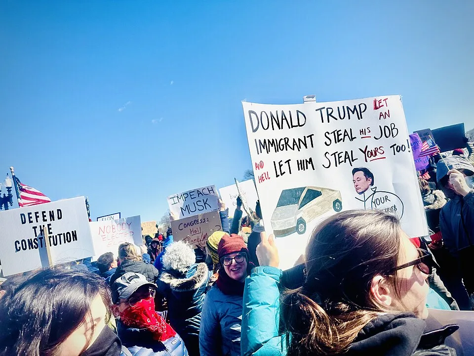 Protest sign reading “Donald Trump let an immigrant steal his job. Why let him steal yours too!”