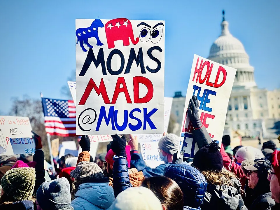 Protest sign reading “Moms mad @ Musk”