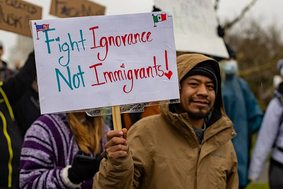 Protest sign reading “Fight ignorance, not immigrants!”