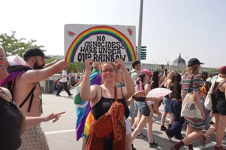 Protest sign reading “No genocides & wars under our rainbow”, photographed in Lyon, France.