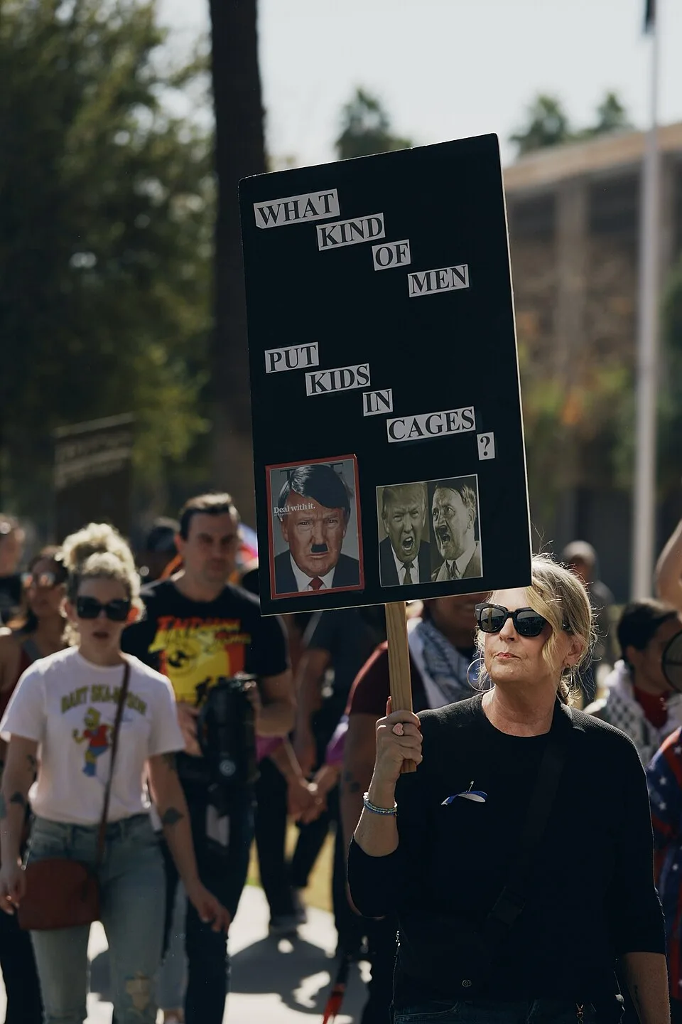 Protest sign reading “What kind of men put kids in cages?”