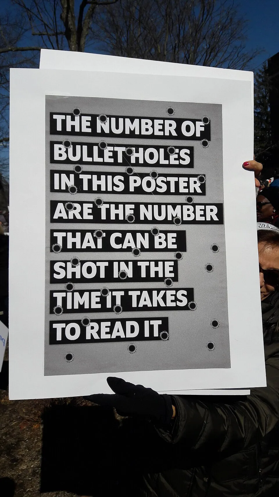 لافتة مظاهرة كُتب عليها «The number of bullet holes in this poster are the number that can be shot in the time it takes to read it»، صُوّرت في Morristown, الولايات المتحدة.