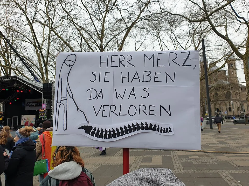 Pancarta con el texto «Herr Merz, Sie haben da was verloren (Rückgrat)», fotografiada en Köln, Alemania.