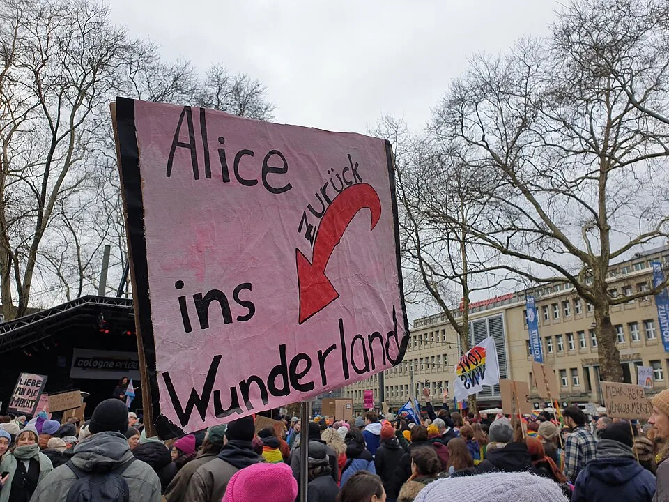 Pancarta con el texto «Alice zurück ins Wunderland», fotografiada en Köln, Alemania.