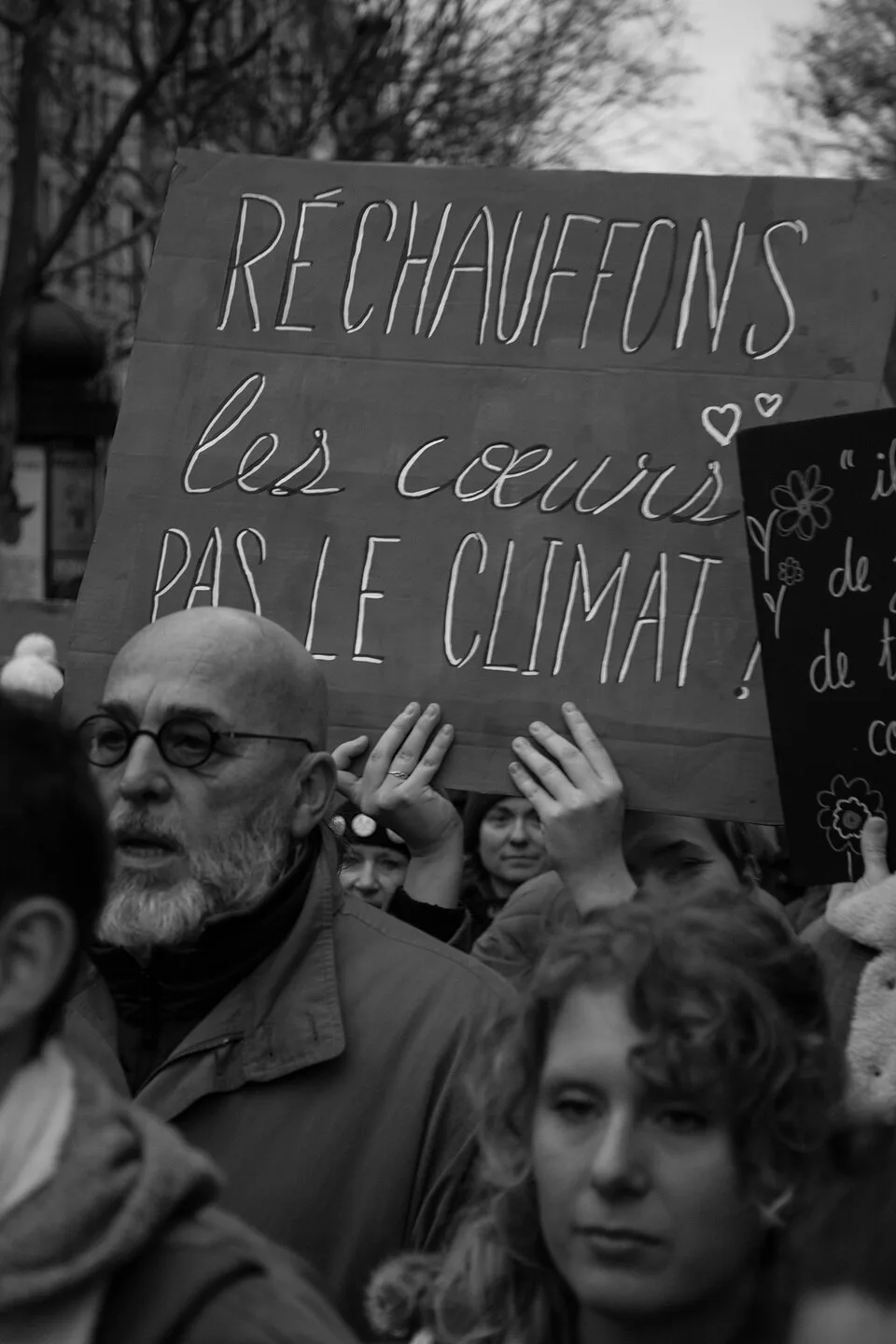 لافتة مظاهرة كُتب عليها «Réchauffons les cœurs, pas le climat»، صُوّرت في Paris, فرنسا.