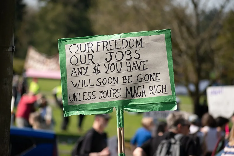 لافتة مظاهرة كُتب عليها «Our freedom, our jobs, any $ you have will soon be gone unless you're MAGA rich»، صُوّرت في Olympia, الولايات المتحدة.