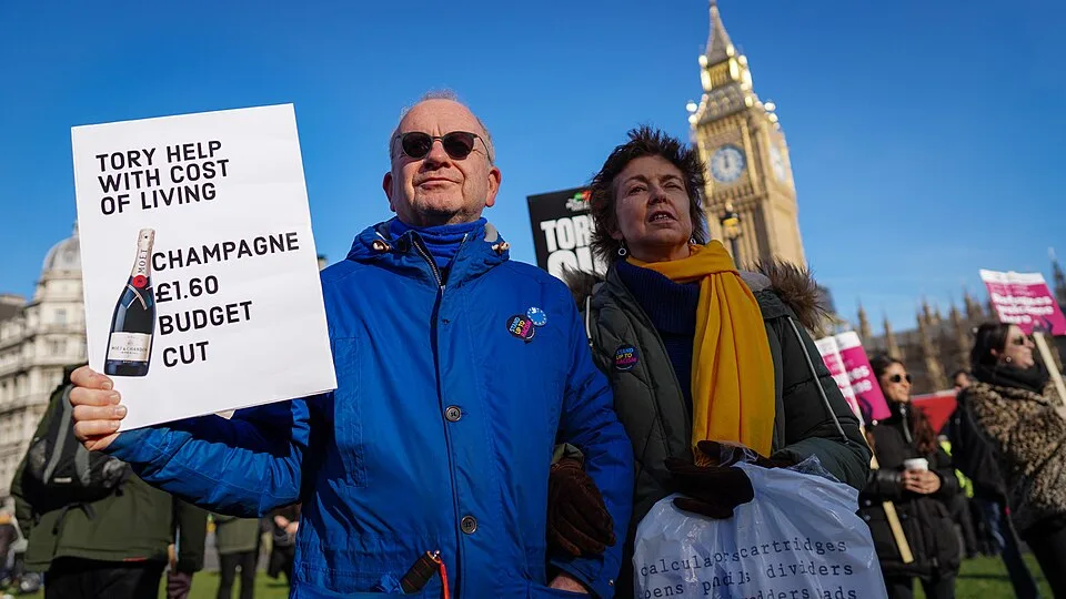 Pancarta con el texto «Tory help with cost of living: champagne £1.60 budget cut», fotografiada en London, Reino Unido.