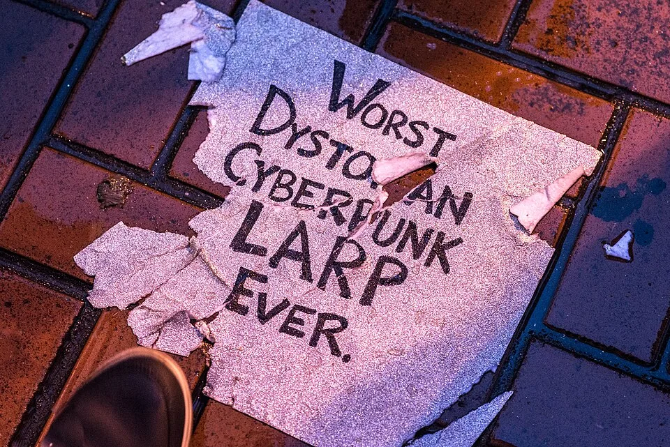 لافتة احتجاج مكتوب عليها «Worst dystopian cyberpunk LARP ever»