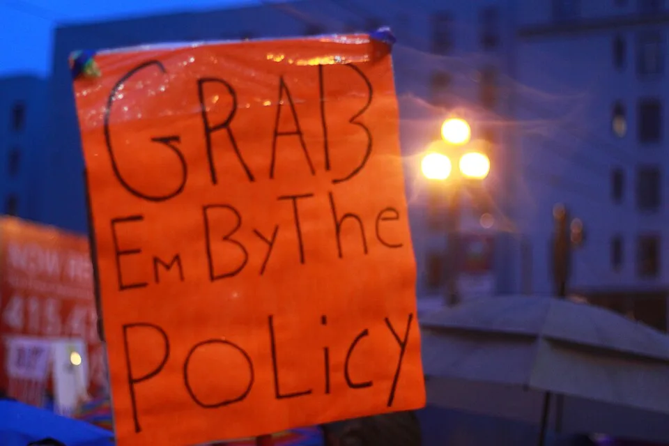 لافتة احتجاج مكتوب عليها «Grab 'em by the policy»