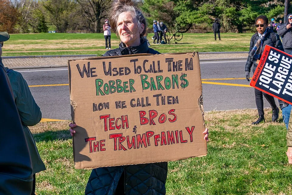 Pancarta con el texto «We used to call them robber barons. Now we call them tech bros. The Trump family?», fotografiada en Washington, Estados Unidos.