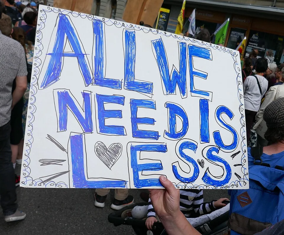 لافتة مظاهرة كُتب عليها «All we need is less»، صُوّرت في Bern, سويسرا.