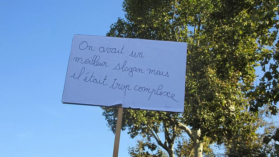 Protestbord met de tekst “On avait un meilleur slogan mais il était trop complexe”