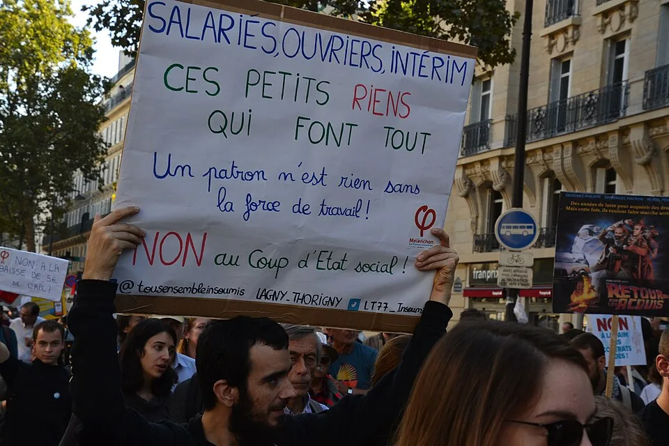 Protestbord met de tekst ‘Salariés, ouvriers, intérim : ces petits riens qui font tout’, gefotografeerd in Paris, Frankrijk.