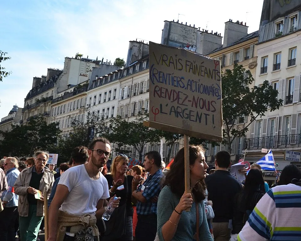 Protestbord met de tekst ‘Vrais fainéants : rentiers, actionnaires. Rendez-nous l'argent !’, gefotografeerd in Paris, Frankrijk.
