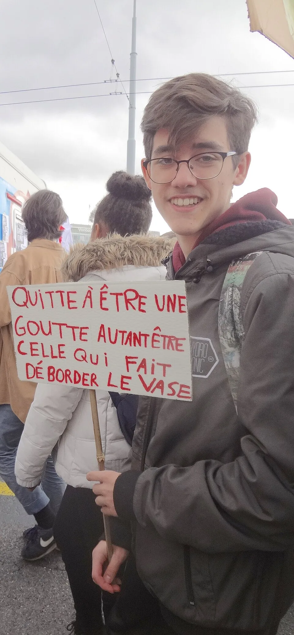Pancarta con el texto «Quitte à être une goutte, autant être celle qui fait déborder le vase», fotografiada en Genève, Suiza.