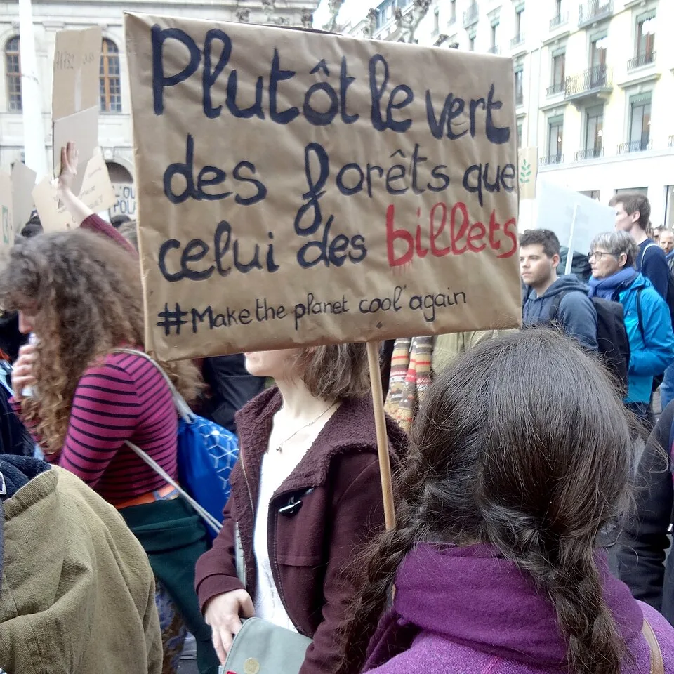 Pancarta con el texto «Plutôt le vert des forêts que celui des billets», fotografiada en Genève, Suiza.