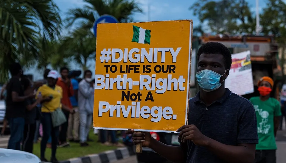 لافتة احتجاج مكتوب عليها «Dignity to life is our birth-right, not a privilege»