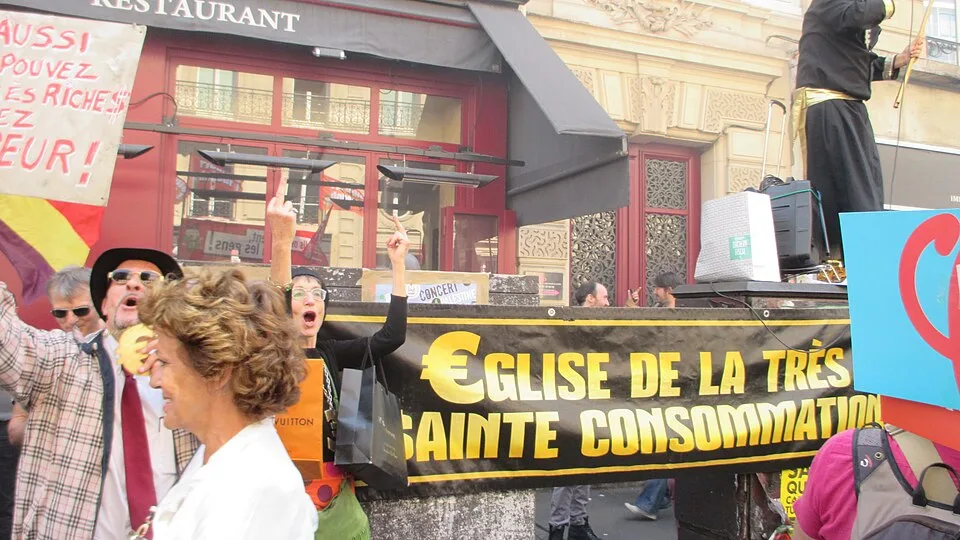 لافتة مظاهرة كُتب عليها «Église de la très sainte consommation»، صُوّرت في Paris, فرنسا.