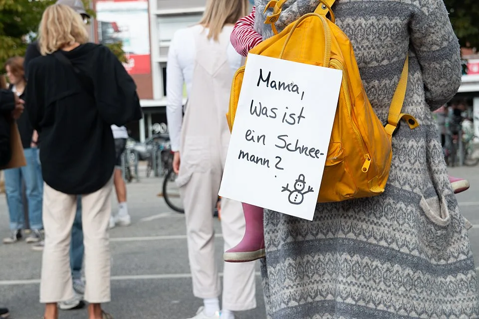 Pancarta de protesta que dice «Mama, was ist ein Schneemann?»