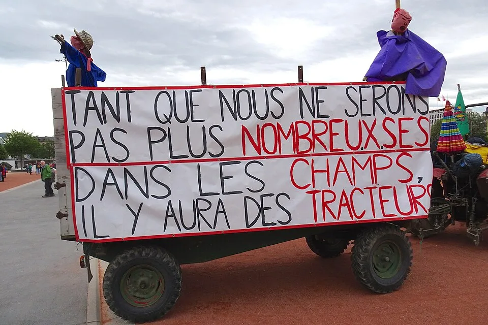 Pancarta con el texto «Tant que nous ne serons pas plus nombreuses dans les champs, il y aura des tracteurs», fotografiada en Genève, Suiza.
