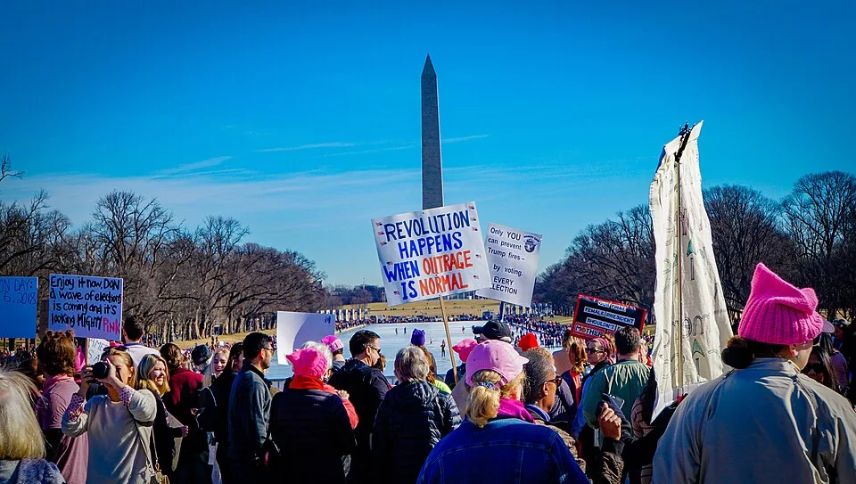 Protest sign reading “Revolution happens when outrage is normal”, photographed in Washington, United States.