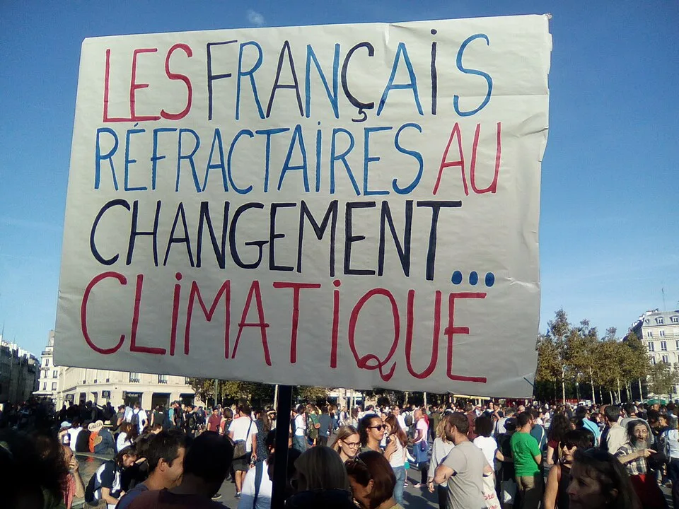 Protest sign reading “Les Français réfractaires au changement… climatique”, photographed in Paris, France.