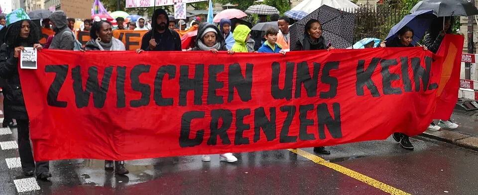 Protest sign reading “Zwischen uns keine Grenzen”, photographed in Bern, Switzerland.