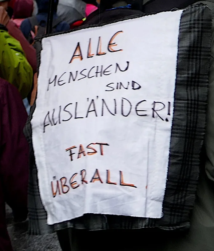 Protest sign reading “Alle Menschen sind Ausländer! Fast überall”, photographed in Bern, Switzerland.