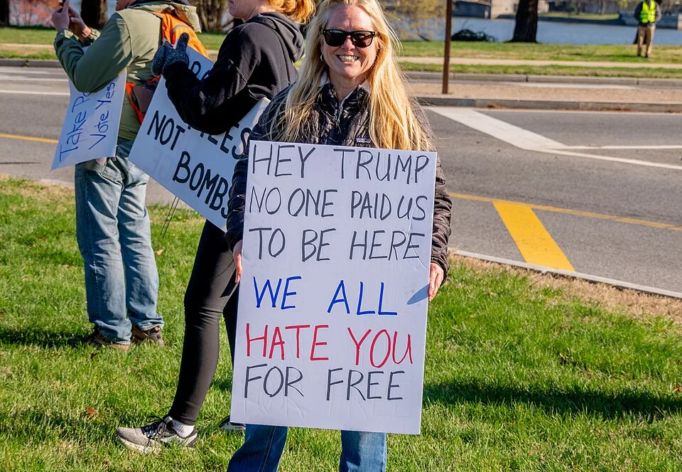 Protest sign reading “Hey Trump, no one paid us to be here. We all hate you for free”, photographed in Washington, United States.