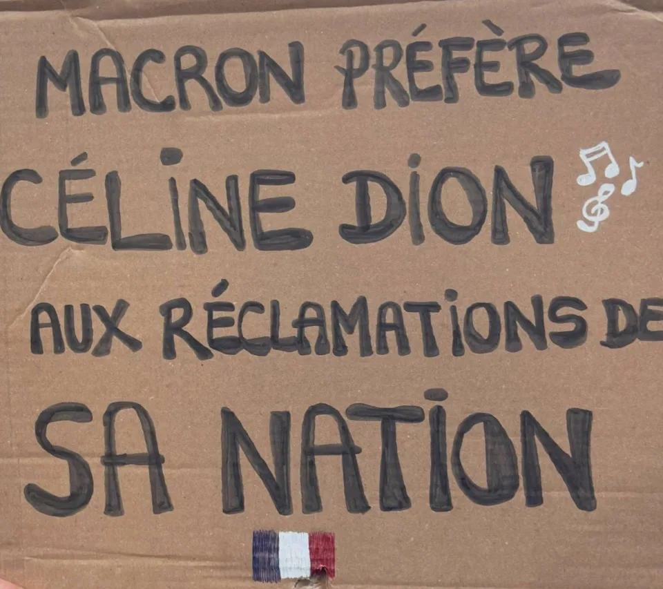 Protest sign reading “MACRON PREFERE CELINE DION AUX RECLAMATIONS DE SA NATION” at “Manifestation du 17 octobre 2026 en France” in France.