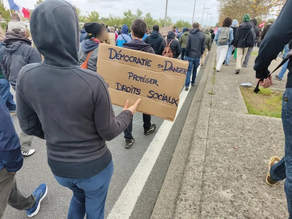 لافتة كُتب عليها «Démocratie en danger. Protéger droits sociaux» خلال «Manifestation du 24 octobre 2026 en France» في Poitiers, فرنسا.